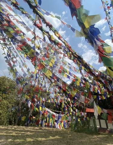 Colorful prayer flags strung up with a blue sky background.