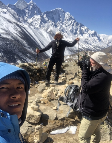 Travelers posing on a rocky trail with trekking poles.