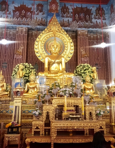 Interior of a temple featuring golden Buddha statues.