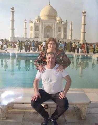 Couple posing in front of the Taj Mahal pool with the monument being distant.