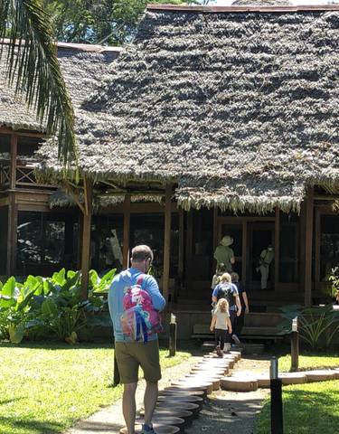 Family walking toward a large thatched-roof building
