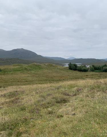 Rolling green hills with distant mountains and small lakes.