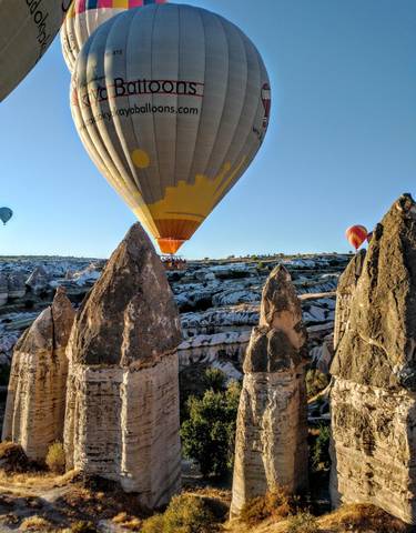 Hot air balloon flying low over unique rock formations.