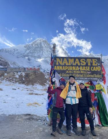 Group of people at the Annapurna Base Camp with mountain in the backdrop.