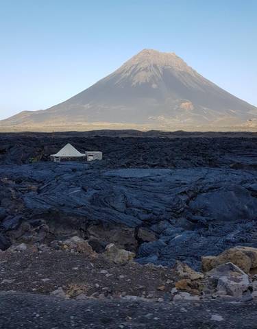 Volcanic landscape with a prominent peak in the background.