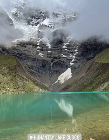 Turquoise lake surrounded by mountains with snow patches.