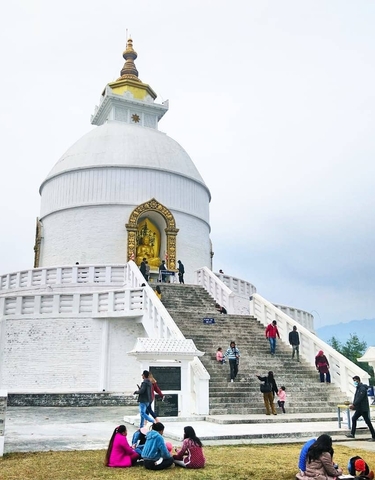 Large white stupa with people at the base and decorative gold elements.