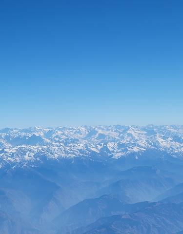 A vast mountain range covered in snow under a clear sky.