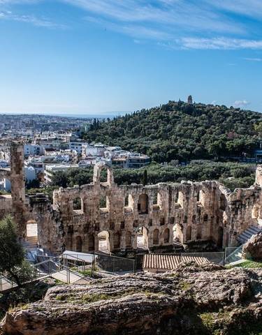 Ancient amphitheater overlooking a cityscape and green hills.