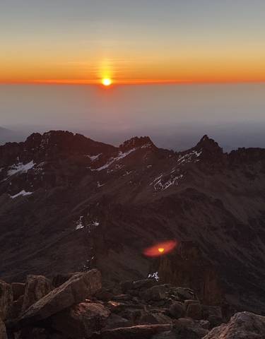 Sunrise over the jagged peaks of a mountain range.