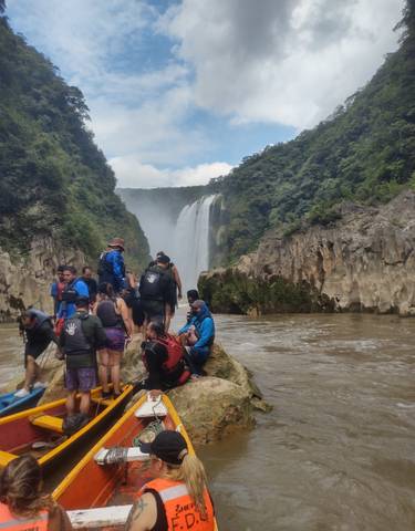Group of people at the base of a large waterfall.