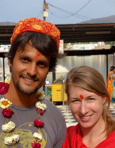 Two people wearing traditional garlands and tilak on their foreheads.