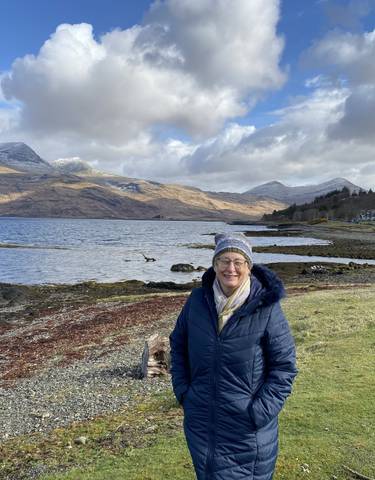 Person standing by a scenic lakeside view.