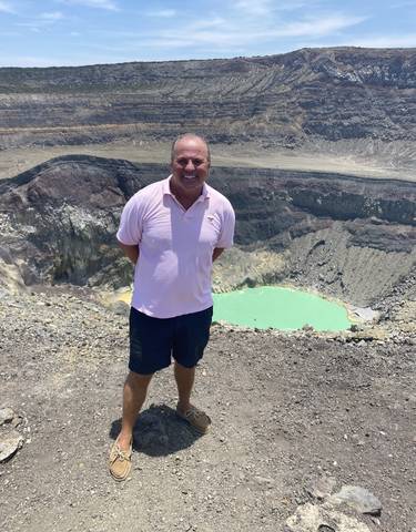 Man standing at the edge of a volcanic crater lake.