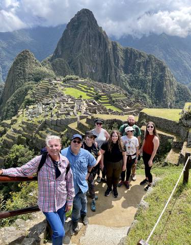 Group of tourists posing with Machu Picchu in the background.