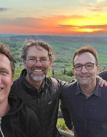 Four men posing during sunset with a scenic landscape backdrop.
