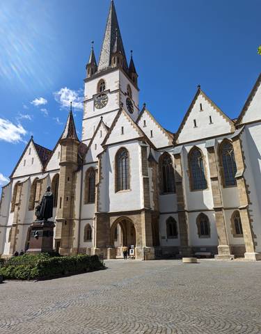 Gothic-style church with arched windows and a statue in front.