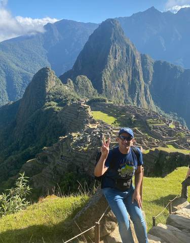 A person posing in front of the ruins of Machu Picchu.