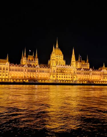 Illuminated parliament building with reflection in water.