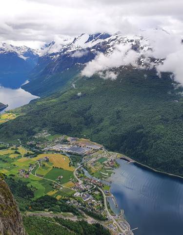 Aerial view of a fjord with snow-capped mountains and a village.