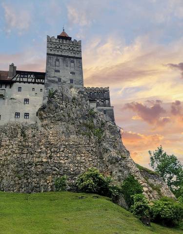 A famous castle on a hill during sunset with flags in the foreground.