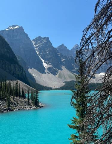 Vibrant turquoise lake with steep mountain peaks.