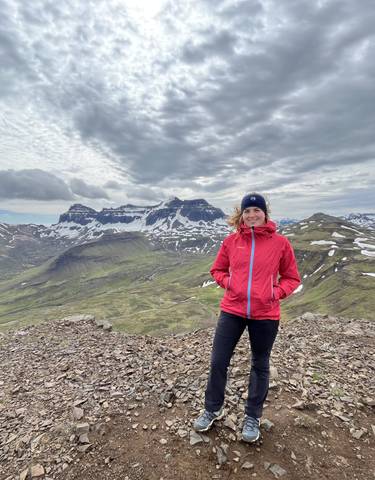 Person posing on a rocky mountain with snow patches.