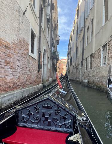 Narrow canal with gondolas passing by
