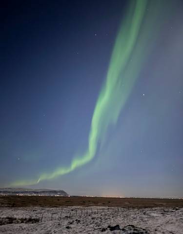 Northern lights in the night sky over a snowy landscape.