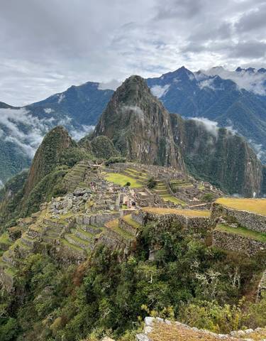 View of Machu Picchu with terraced stone ruins and mountains in the background.