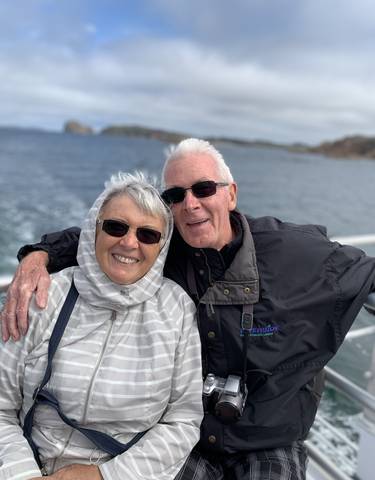 Elderly couple smiling on a boat with water in the background.