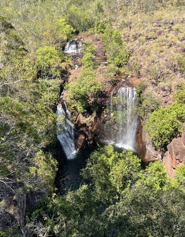 Aerial view of waterfalls surrounded by lush greenery.