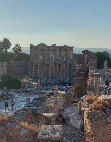 Ancient ruins with trees and people in the background.