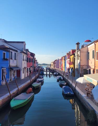 Colorful buildings lining a canal with boats in a sunny setting.