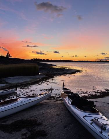 Kayaks by a serene waterfront at sunset.