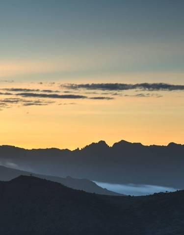 Mountain silhouette against a colorful sky at sunrise.