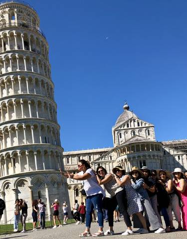 People posing in front of the Leaning Tower of Pisa.