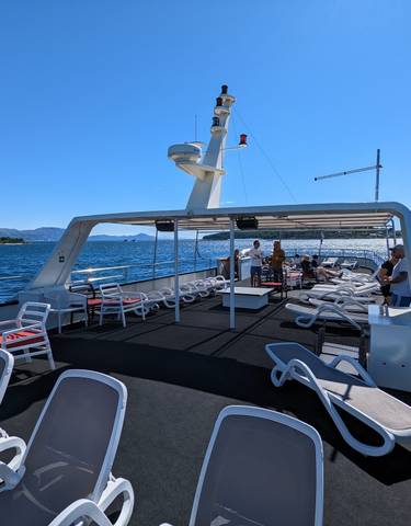 Deck of a yacht with lounge chairs under a clear blue sky.