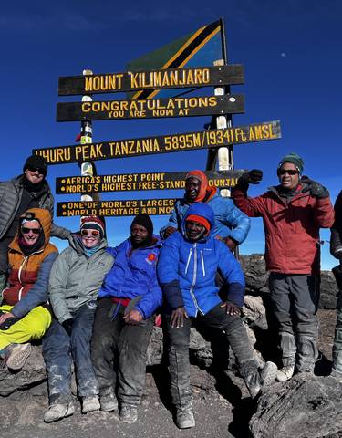 Group celebrating at the Uhuru Peak summit marker.