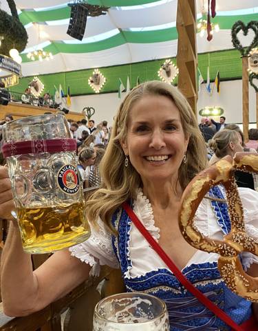 Woman in traditional dress holding a large beer mug and pretzel.
