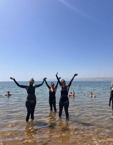 People covered in mud standing in the Dead Sea.