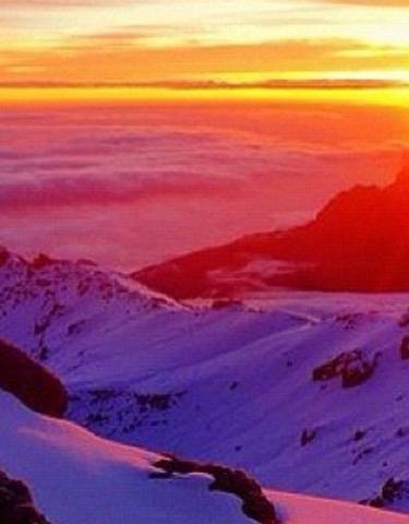 Sunrise over a snow-covered mountain landscape with a sea of clouds.