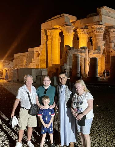 Group of people in front of illuminated ancient ruins at night.