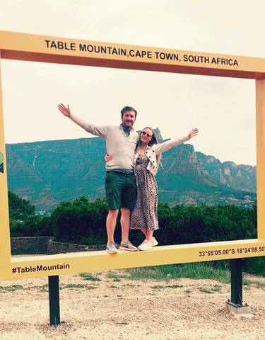 Couple standing in a picture frame with mountain in the background.