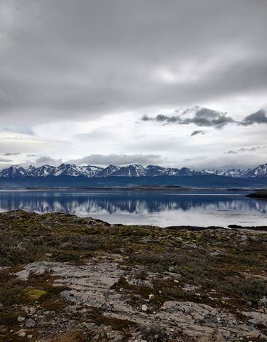 Mountain range with snow caps reflected in a calm lake.