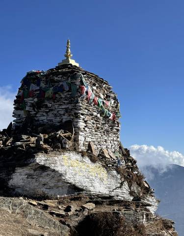 Chorten monument with prayer flags against a clear sky.