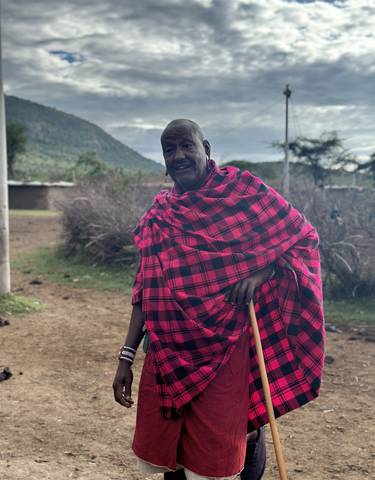 Person in traditional Maasai attire with landscape background.