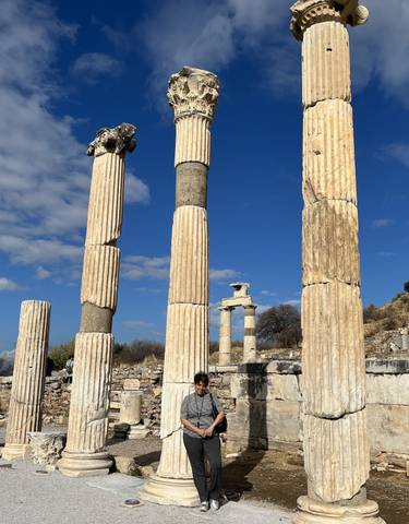 Person in front of ancient columns under a blue sky.