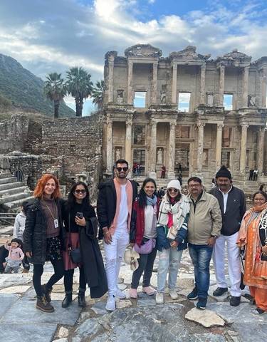 Group of tourists posing in front of ancient ruins.