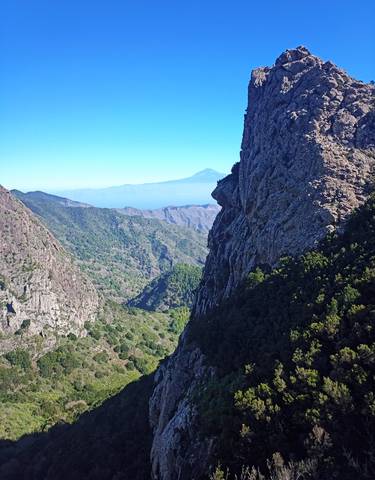 Mountain range with a distant peak under a clear blue sky.
